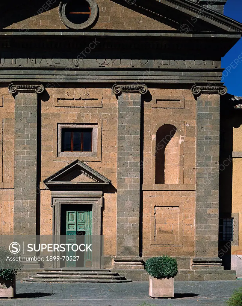 Italy, Lazio, Capranica (Viterbo), Church of Madonna del Piano. Detail. View of the tripartite facade of the church with Ionic pilasters, triangular pediment, entablature, oculus, tympanum and the bichromy grey-yellow.