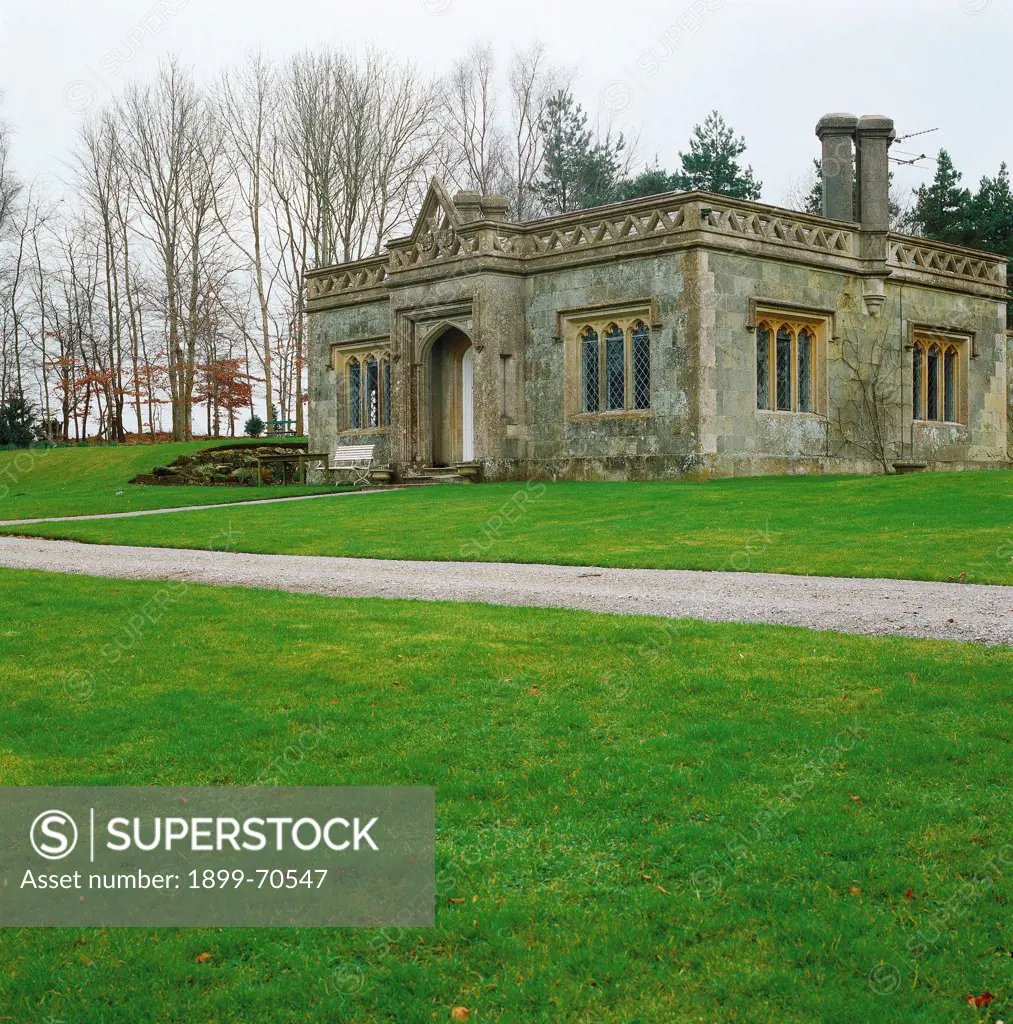 United Kingdom, Stourhead (Wiltshire). Detail. In the park near a path, front view of a building with balustrade, three-light windows and parapet.