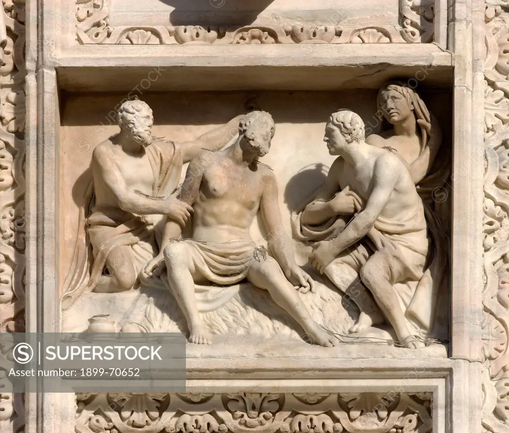 Italy, Lombardy, Milan, Duomo, Facade. Detail. Two men oblige Job to sit on on a dunghill.