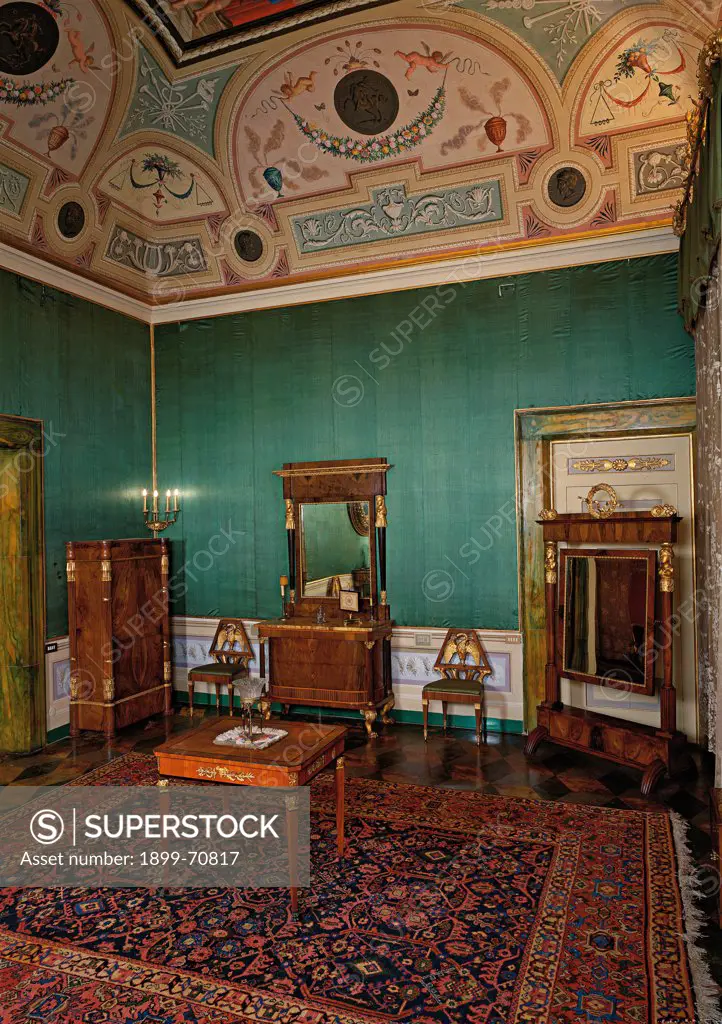 Italy, Tuscany, Siena, Palazzo Chigi-Saracini. Detail. A room decorated with veneered walnut wood furnishings, green upholstery for the walls, a persian carpet in the middle of the floor and the frescoed vault ceiling.