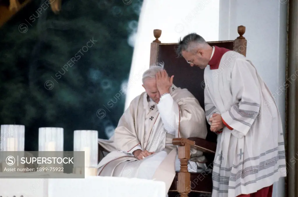 Sitting on his chair, Pope John Paul II, born Karol JÑzef Wojtyla brings a hand on his forehead, while a primate looks towards him. Northern Ireland, October 1979.