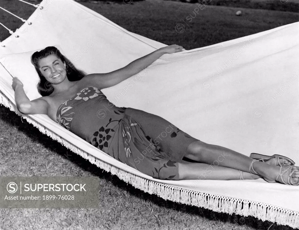 American women's swimming champion and actress Esther Williams lying on a hammock. USA, 1950s.