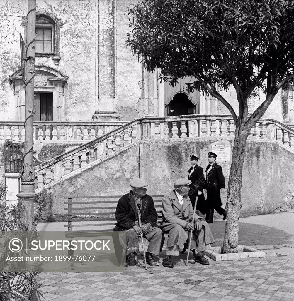 Two old Sicilian men sitting on a bench at the foot of the St. Joseph church. Taormina, 1955.