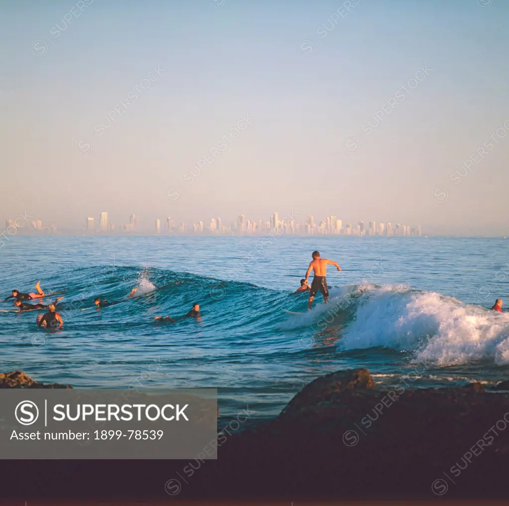 Surfers at dawn view north to Surfers Paradise, Currumbin Beach, Gold Coast, Queensland, Australia