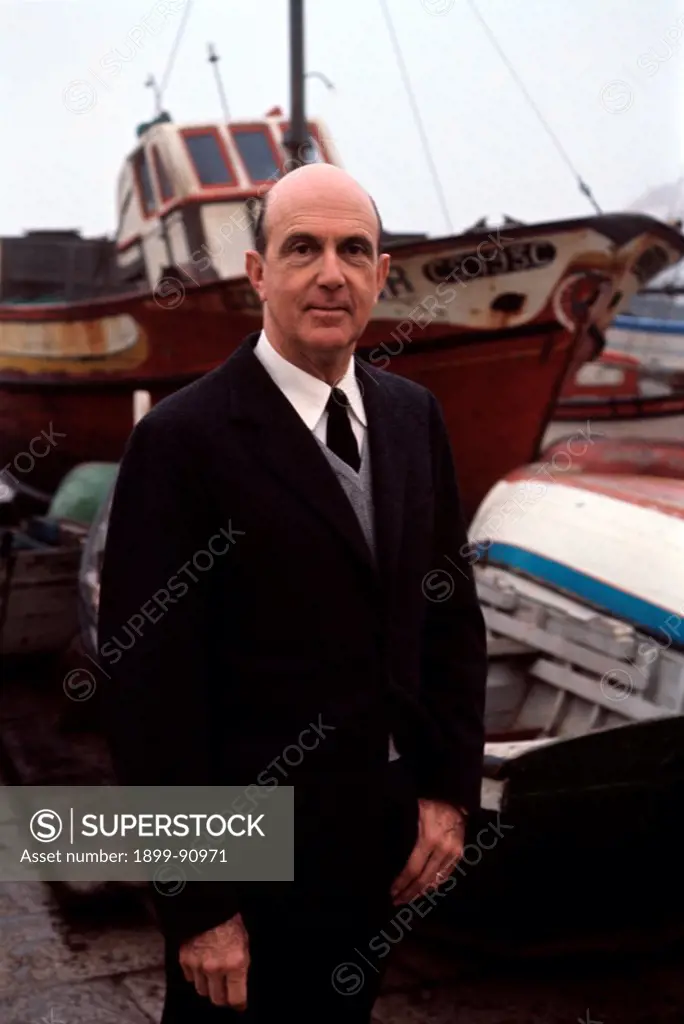 Umberto II of Italy smiles on Cascais beach where was exiled; behind him are some boats. Cascais (Portugal), 1965.