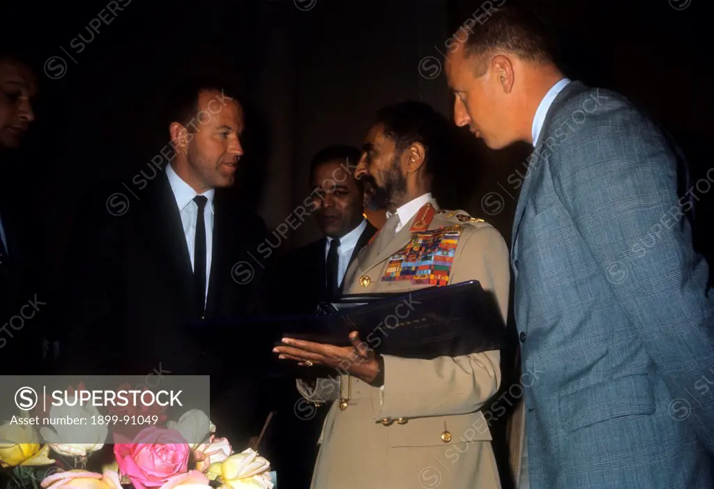 Haile Selassiè, king of Ethiopia, talking with two American astronauts; in his hands he is holding a folder. Addis Abeba (Ethiopia), 1965.