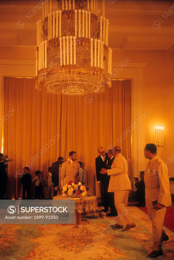 Hailè Selassiè, king of Ethiopia, in his royal building together with other political and military figures; the king is wearing a uniform and is standing in front of a sofa throne. Adis Abeba (Ethiopia), 1965.