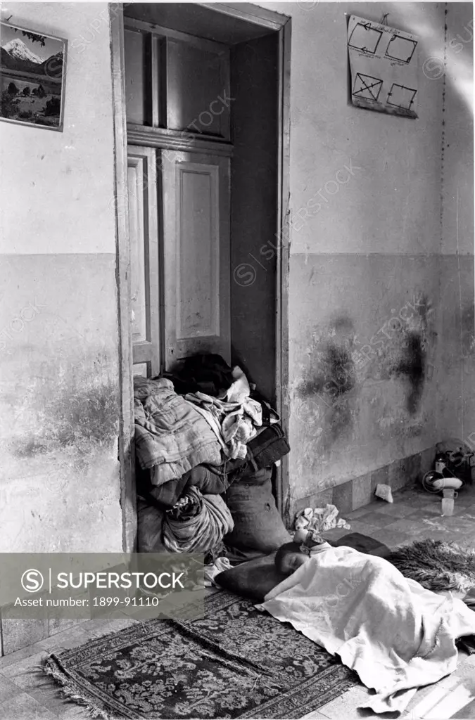 A refugee young boy is sleeping on the ground, under a sheet on a carpet in a house. Six-Day War. Amman (Jordan), 1967.