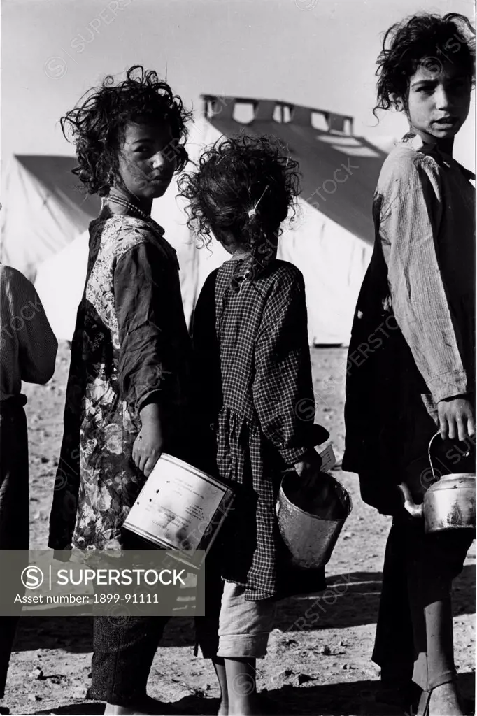 Some young girls in the refugee camp of Wadi Dlails queue holding containers in their hands, one month after the Six-Day War. Jordan, July, 1967.