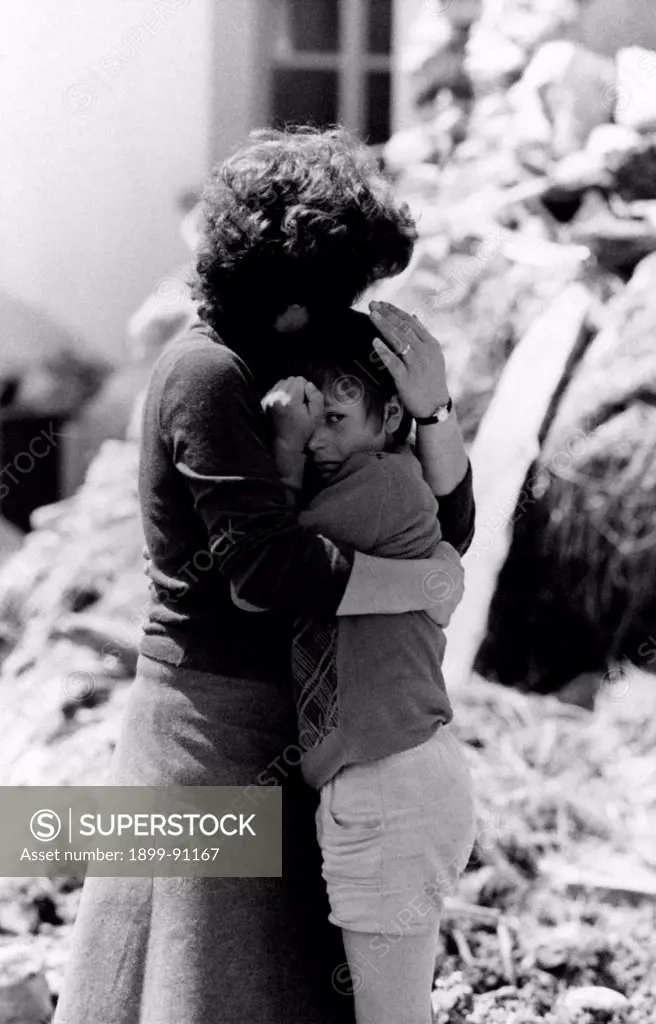 A woman hugs her son protectively, in front of the ruins of their house destroyed in the earthquake of the 6th May 1976. Tomba di Buja (UD), Italy, July 1976.