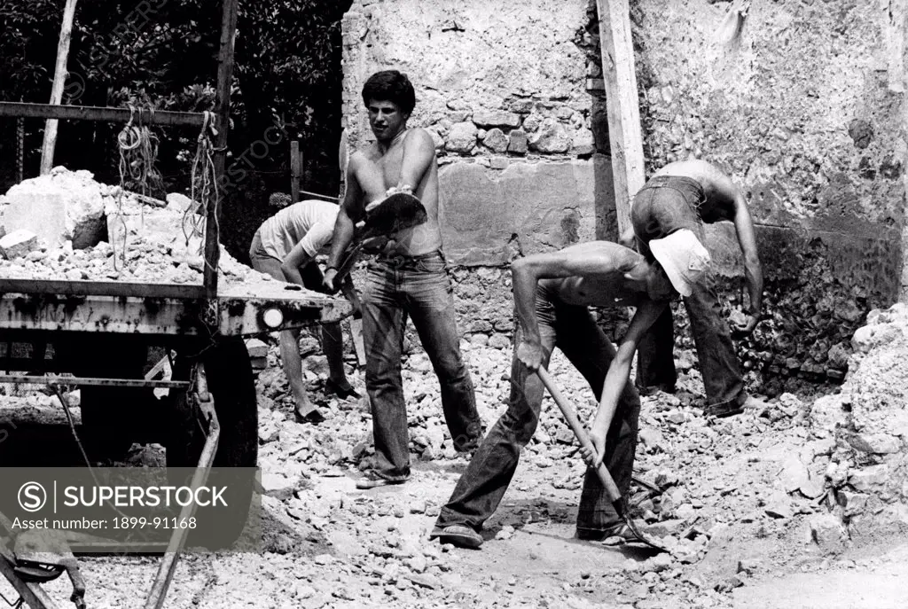 A group of young men coming from the Piemonte region of Tortona work on the reconstruction of the commune of  Tomba di Buja; The young men equipped with shovels, are removing rubble from the roads.  Tomba di Buja (UD), Italy, August 1977.