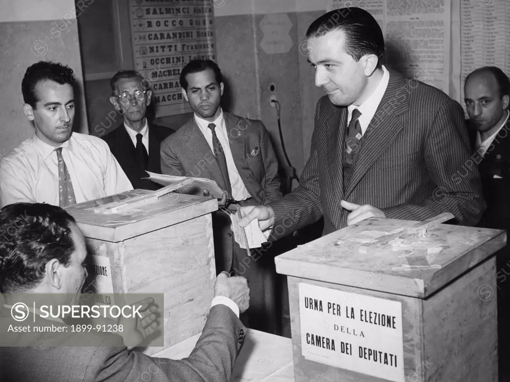 Giulio Andreotti at a polling station during the election of the Chamber of Deputies; he is handing his ballot paper over to a vote counter. Rome (Italy), June 7, 1953.