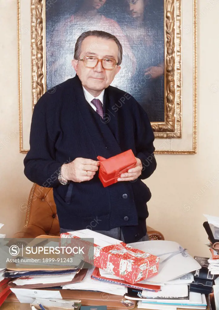 The Christian Democracy party senator Giulio Andreotti is standing behind his desk of his office, with a Christmas present in his hands. Italy, 1988.