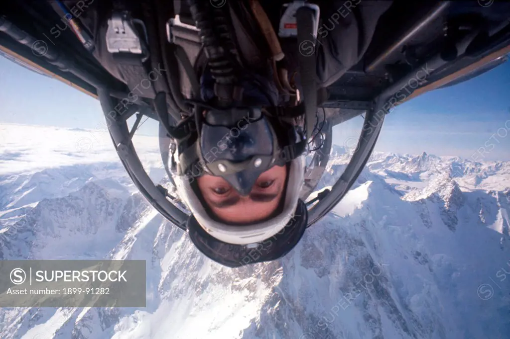 A pilot on a flight backhand during an exercise on board an aircraft of the Italian Airforce. In the background the Alps. 1970