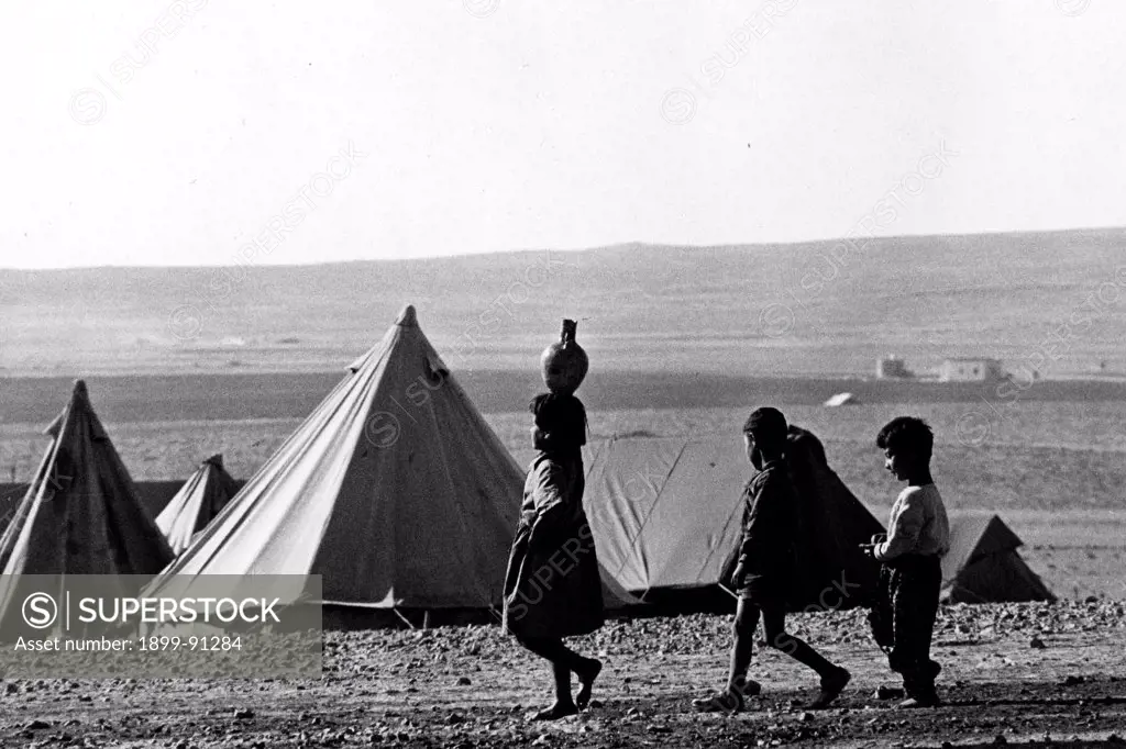Children bring water and food to the tent in a refugee camp in the desert after the attacks of Black September in Jordan in 1970.