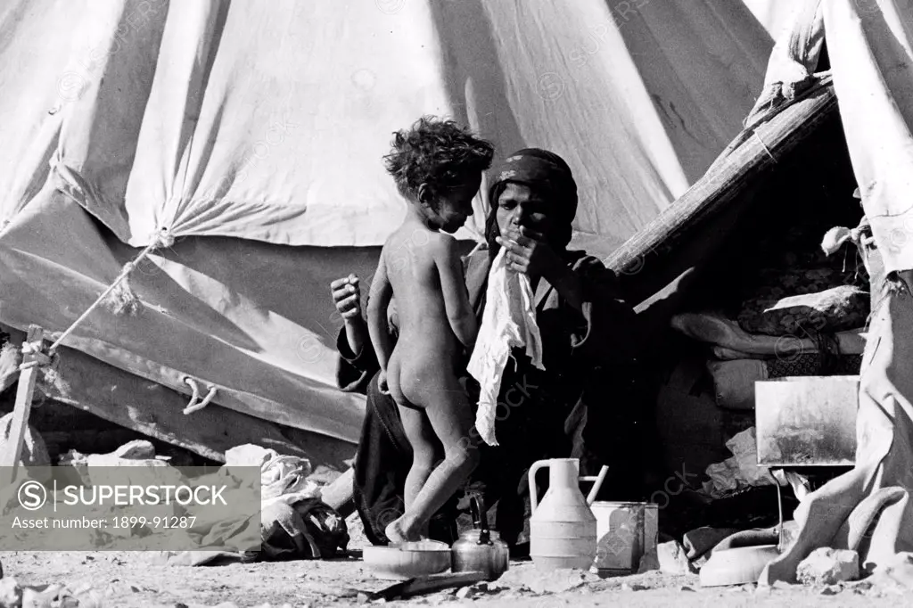 Mother washes her son in front of a tent in a refugee camp in the desert, during the Black September. Jordan, 1970.