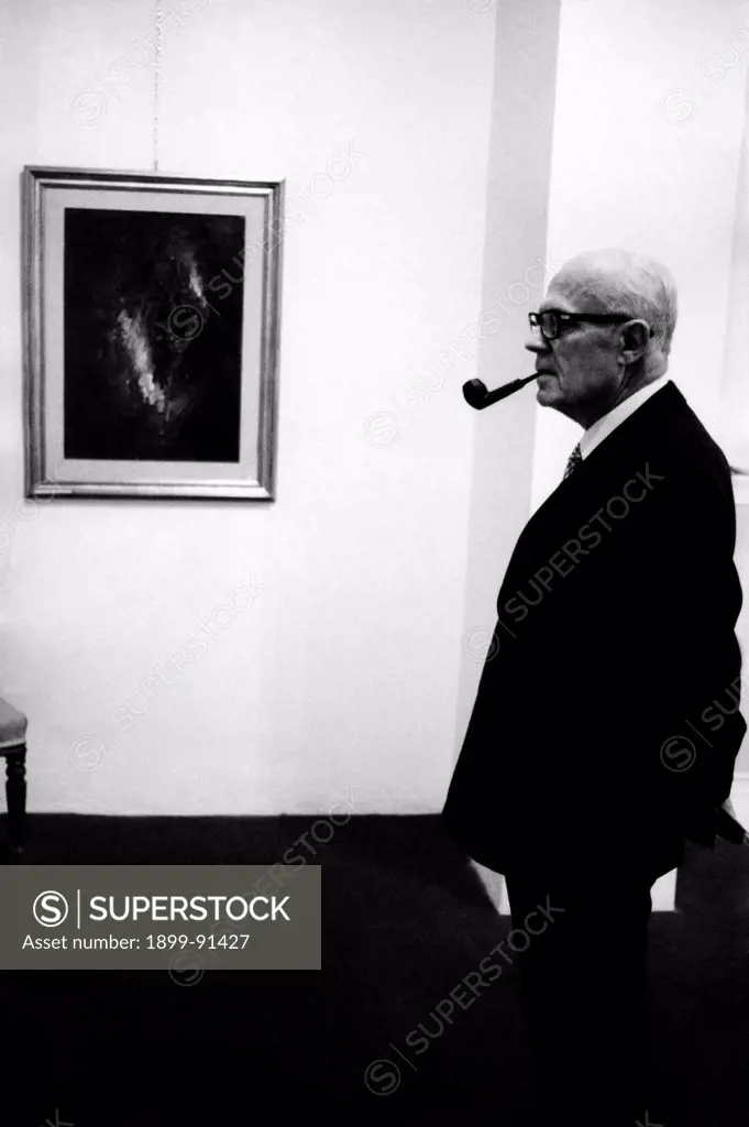 President of the Chamber of Deputies of the Italian Republic Sandro Pertini visiting a painting exhibition. Behind him, a painting of the exhibition. 1972