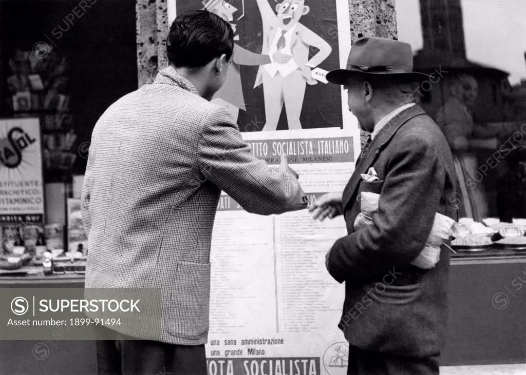 Two men observing a poster of the Italian Socialist Party (PSI). Italy, 1951
