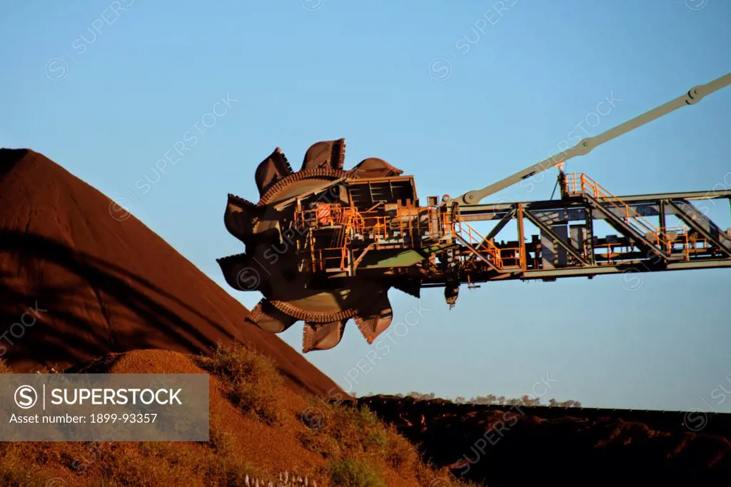 Bucket wheel of a mining reclaimer moving stockpiled iron ore to conveyor belts which transport it to train loading facilities, iron ore is currently Australia's largest export earner and the mines of the Pilbara operate around the clock every day of the year, Newman, Pilbara region, Western Australia,6/5/2011