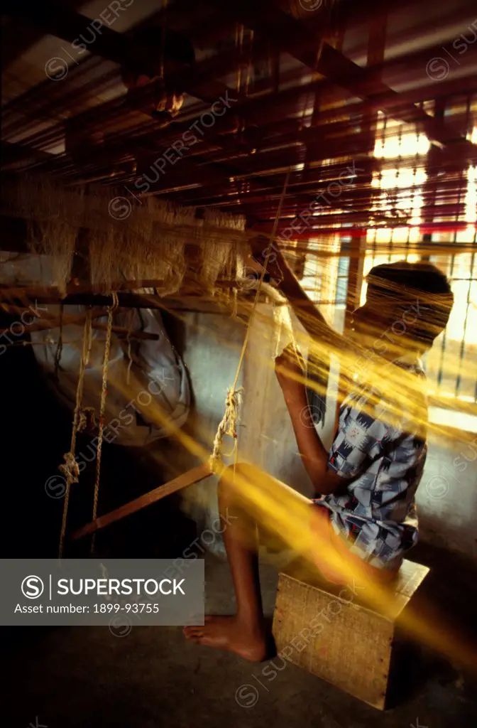 Boy helping weaver under handloom in Kanchipuram, India,04/10/1998