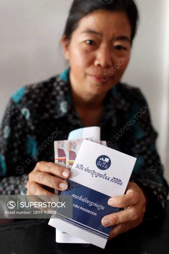 Chamroeun microfinance client showing her passbook and reimbursement, Cambodia,02/16/2011