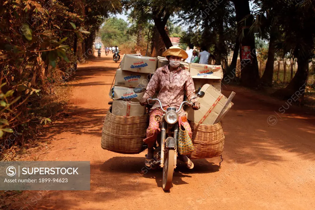 Woman transporting goods on a dirt road, Cambodia.,02/14/2011