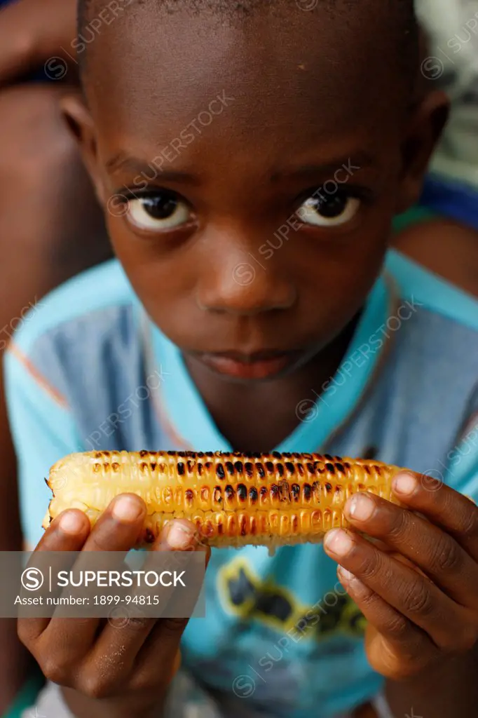 African boy eating corn, Lome, Togo.,06/28/2010