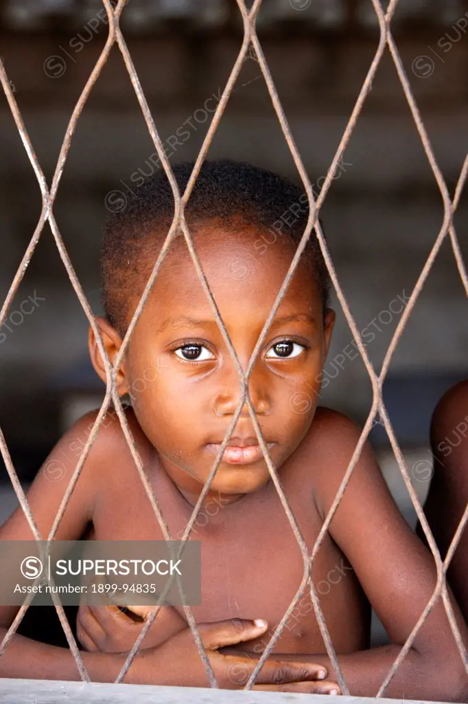 African boy looking through a mesh, Lome, Togo.,02/11/2009