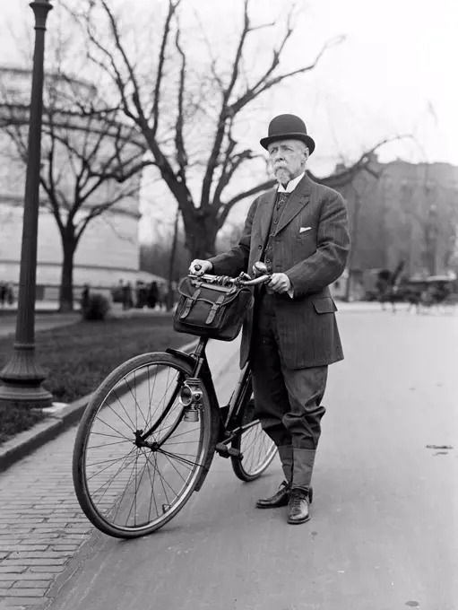 Old man standing next to his bicycle circa 1914. 