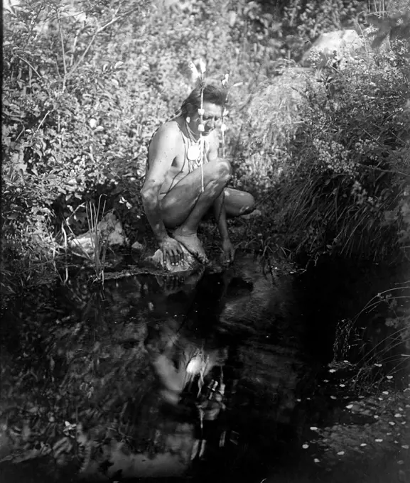 Edward S. Curtis Native American Indians - Crow Indian kneeling beside water gazing at his reflection ca. 1905. 