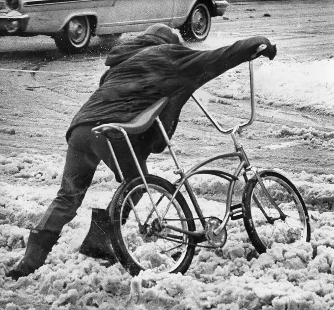 Boy Pushing Bike Across Slushy Street November 1966. 