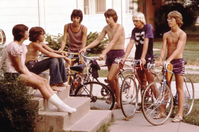 Teens on bicycles talk in front of a home in New Ulm, MN in 1973. 