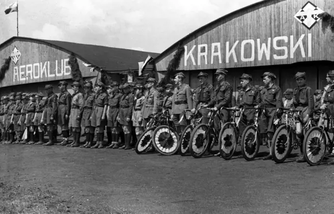 Cyclists with decorated bikes in front of the hangar of the Krakow Aeroclub at the Rakowicki airport ca. May 1, 1937. 