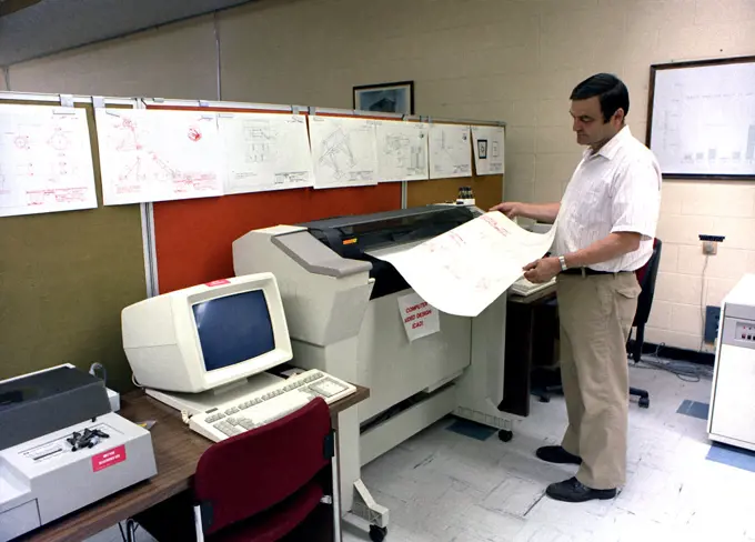 An engineer monitors a printout as he uses the Computer Aided Design (CAD) system to develop the mount system for the tail section of the B-1 bomber.. 