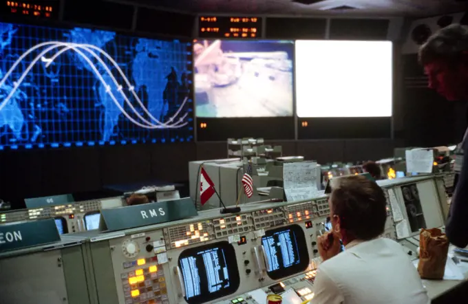 (12 Nov. 1981) --- An overall view of activity in the mission operations control room (MOCR) in Houston's Mission Control Center (MCC) as viewed from the second front row of consoles during the STS-2 mission. The remote manipulator system (RMS) console is in the immediate foreground. Note TV transmission on the Eidophor screen at front of MOCR and shuttle orbiter marker on tracking map at left indicating the vehicle's location over the Hawaiian Islands.