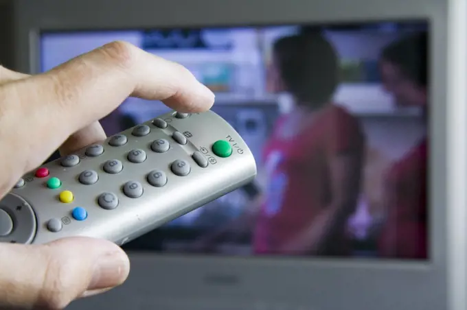 Hand holding remote control for television, about to press the standby button, United Kingdom. In standby mode most electrical appliances use almost as much energy as they do when they are working. By reducing the amount of items left on standby, energy use can be reduced.