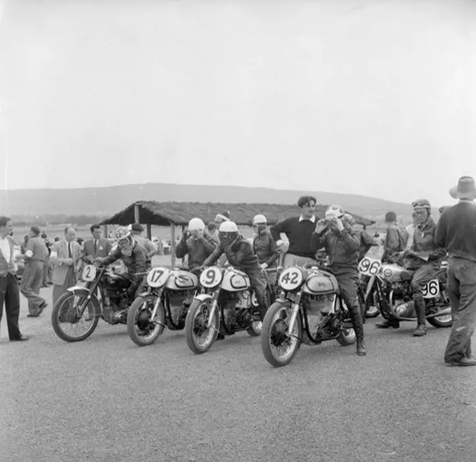 Nakuru motorcycle race. A group of riders sit astride their numbered motorcycles, adjusting their goggles at the start of a race. Nakuru, Kenya, 6 August 1956. Nakuru, Rift Valley, Kenya, Eastern Africa, Africa.