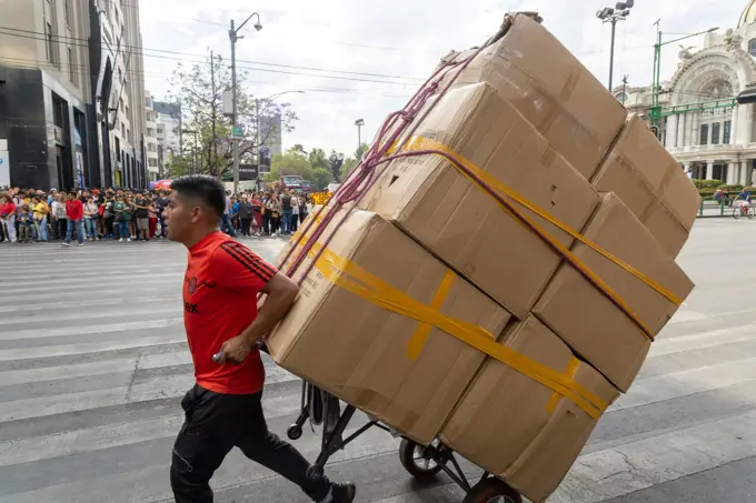 Man pulling cart loaded with large cardboard boxes, city center Mexico City, Mexico.