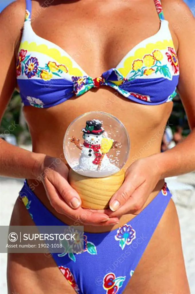Antigua young woman in bikini bathing suit holding a snow globe