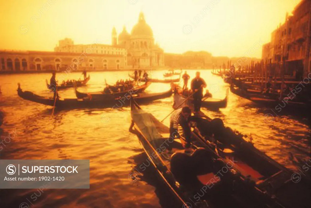 Italy Venice gondoliers on the Grand Canal at sunset with Santa Maria della Salute in the background