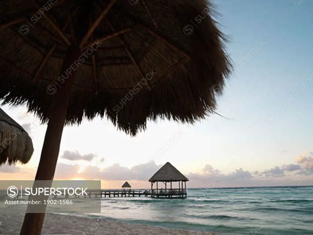 Mexico Quintana Roo Yucatan Peninsula Akumal Mayan Riviera pier with palapa jutting out on to the water from the beach at sunrise with surf
