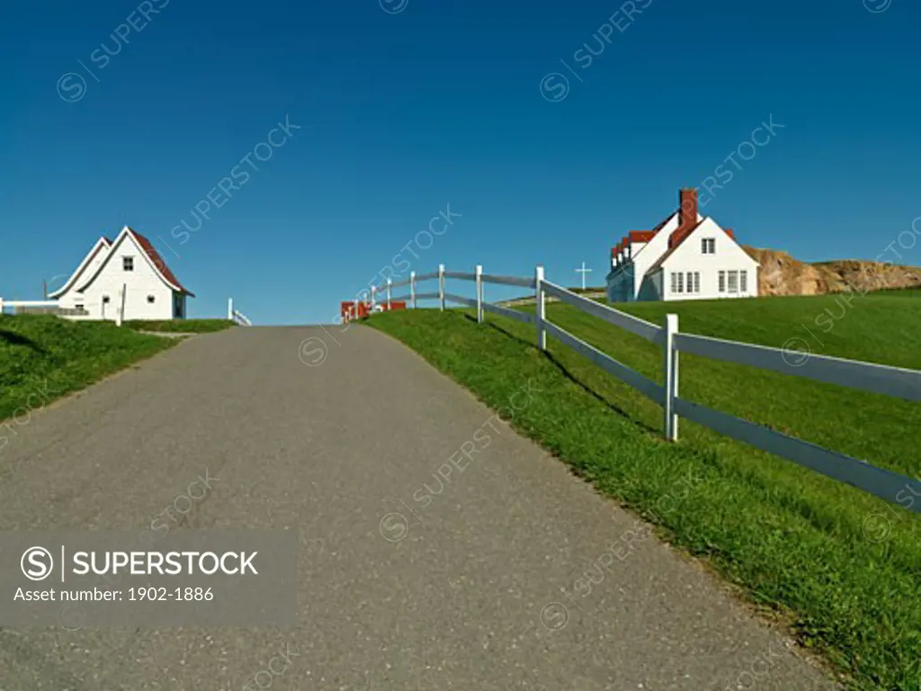 Canada Quebec Gaspesie Perce road lined with white fence and white clapboard homes in the town of Perce