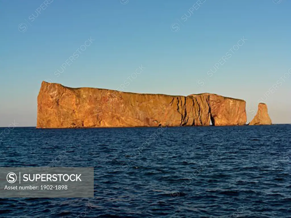 Canada Quebec Gaspesie Perce Perce Rock illuminated at sunset at high tide and the Gulf of Saint Lawrence