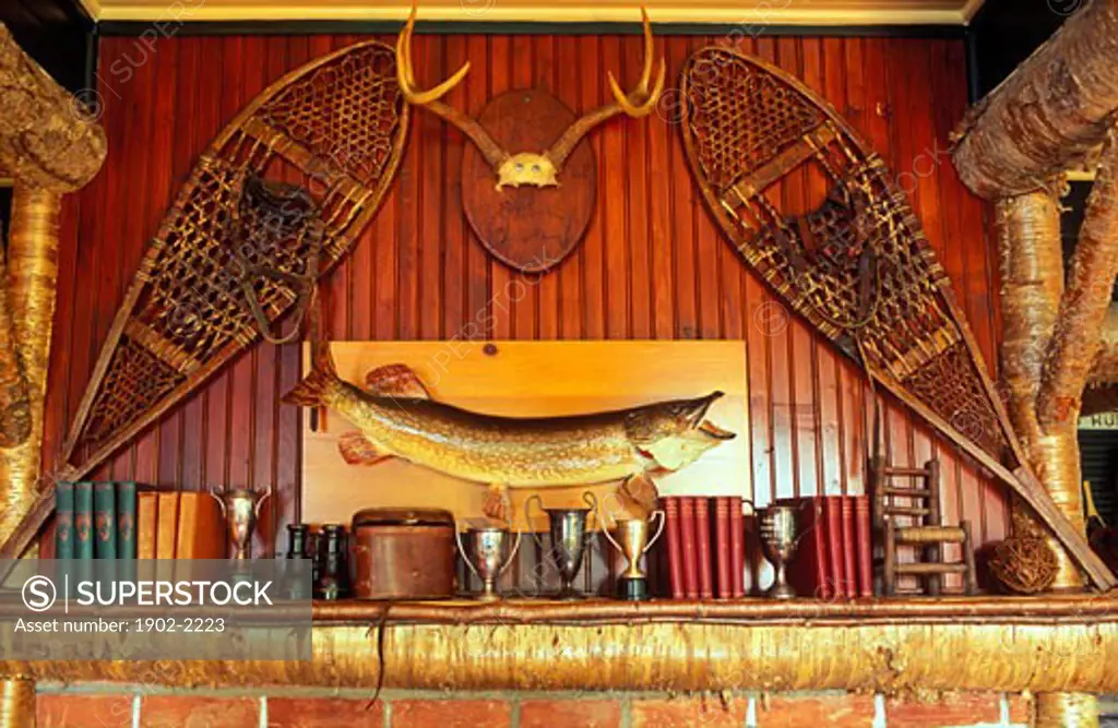 USA New York Lake Placid snow shoes fish trophies and books decorating a rustic mantle piece