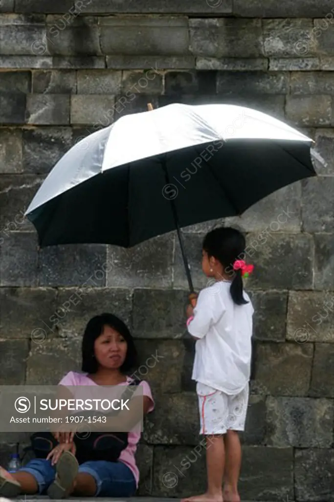 Woman and child with umbrella during the visit of the Borobudur temple Java Indonesia