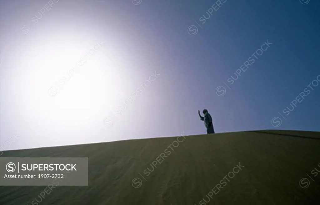 A Touareg walking on the crest of a dune in the Hoggars tassilis algerian desert