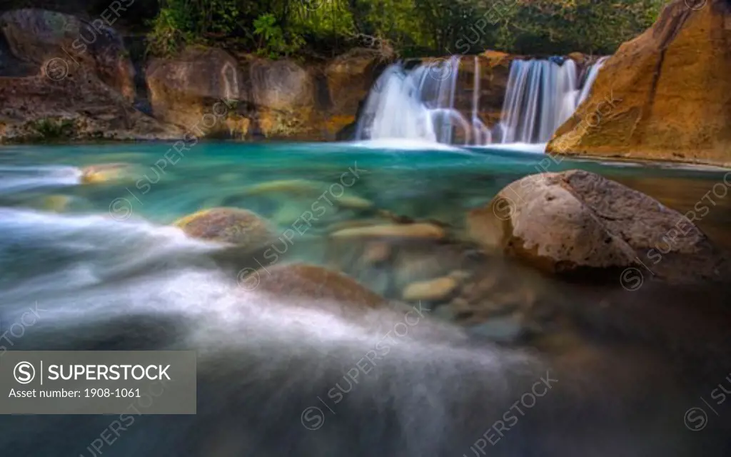 Scenic shot of a spectacular Costa Rica tropical waterfall surrounded by trees and red rocks complimented by the motion blur of the rushing water Rincon de la Vieja