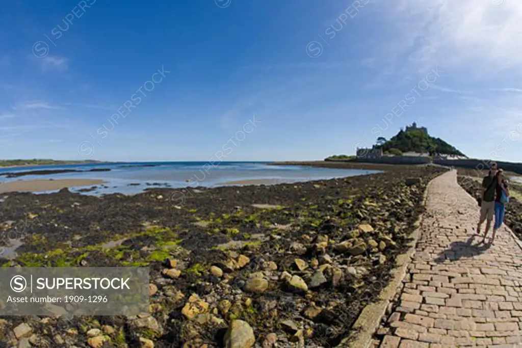 Young couple stroll along St Michaels Mount causeway in late summer sunshine Marazion Cornwall West Country England UK United Kingdom GB Great Britain British Isles Europe EU
