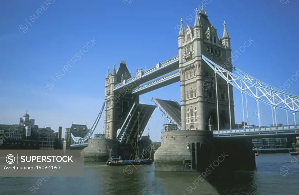 Tower Bridge over the River Thames opening to let an old sailing vessel with tall mast underneath London England UK United Kingdom GB Great Britain Europe