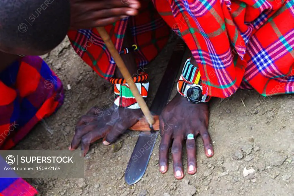 Masai warriors making fire in Masai village on safari in Masai Mara National Nature Reserve Kenya East Africa